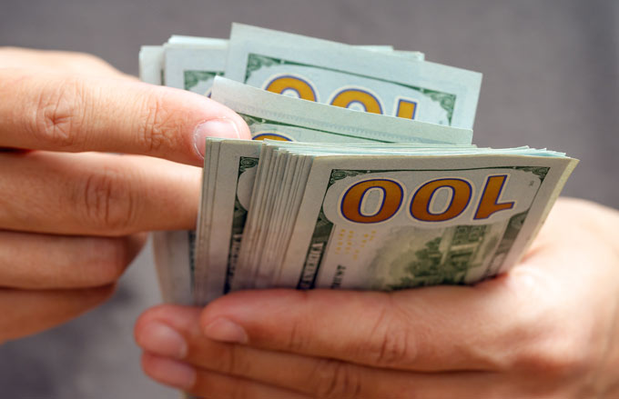 hands holding stack of hundred dollar US bills